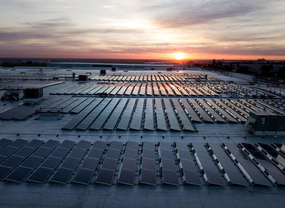 A warehouse rooftop covered in solar panels at sunset