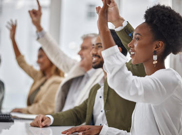 Employees with hands raised ready to answer a question