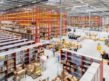 Interior warehouse angled view from top of the stairs in Nieuwegin Distribution Center 2 in the Netherlands with red and yellow racking and lots of boxes