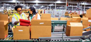 Warehouse workers talking next to a conveyor system