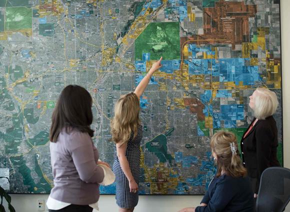 4 women looking at a map of the Denver area on a wall