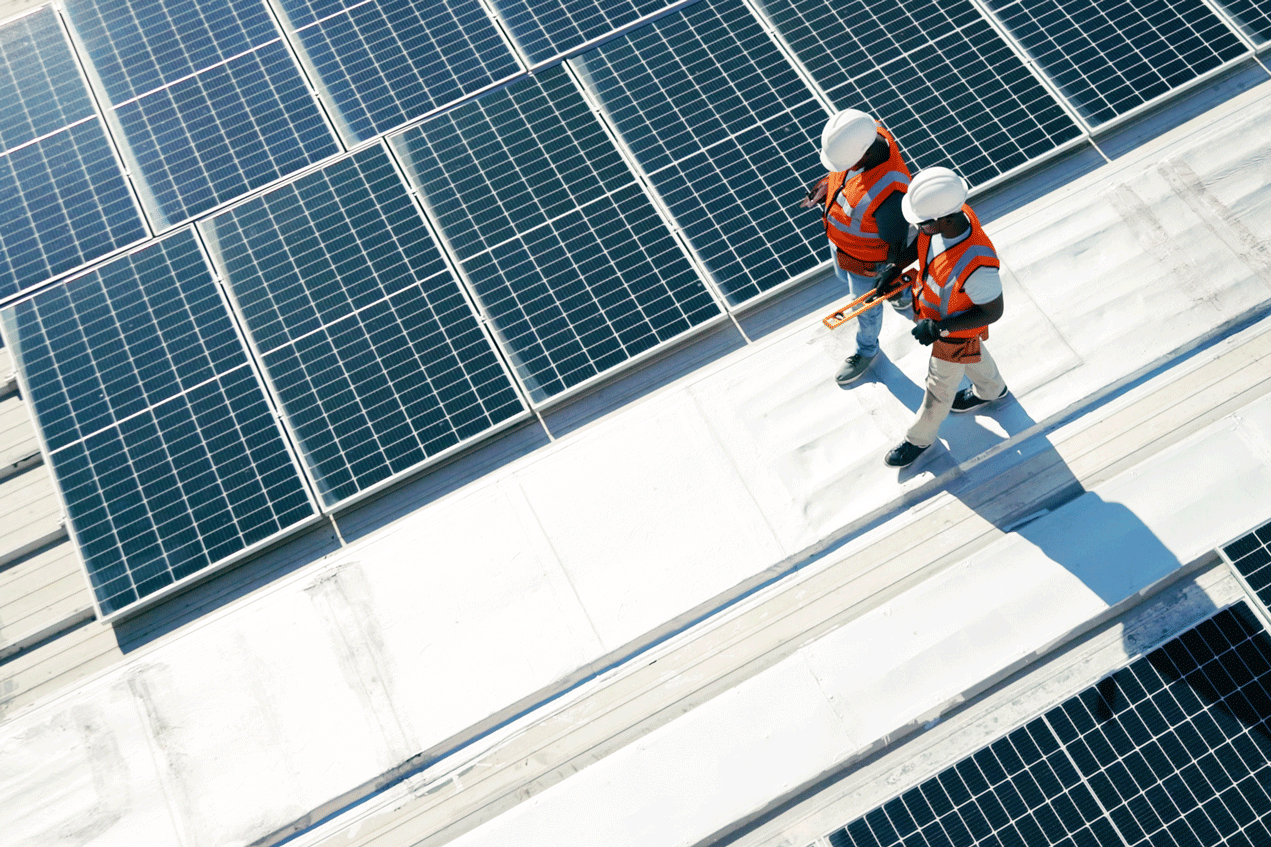 Two people walking on a roof with solar panels